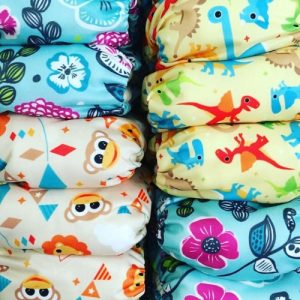 Close up of cloth diapers stacked. 3 different printed fabrics. circus, dino and hawaiin