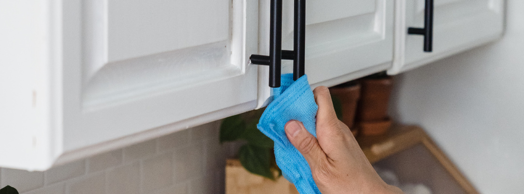 Person cleaning cabinet handles with a cloth